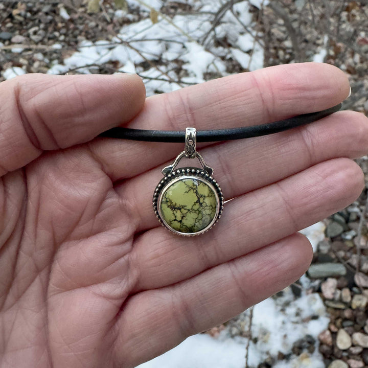 Small green turquoise pendant shown in a hand for size reference.