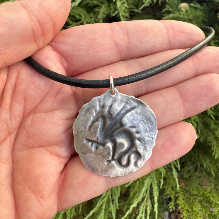 Back of handmade sterling silver dragon medallion showing the impression die relief