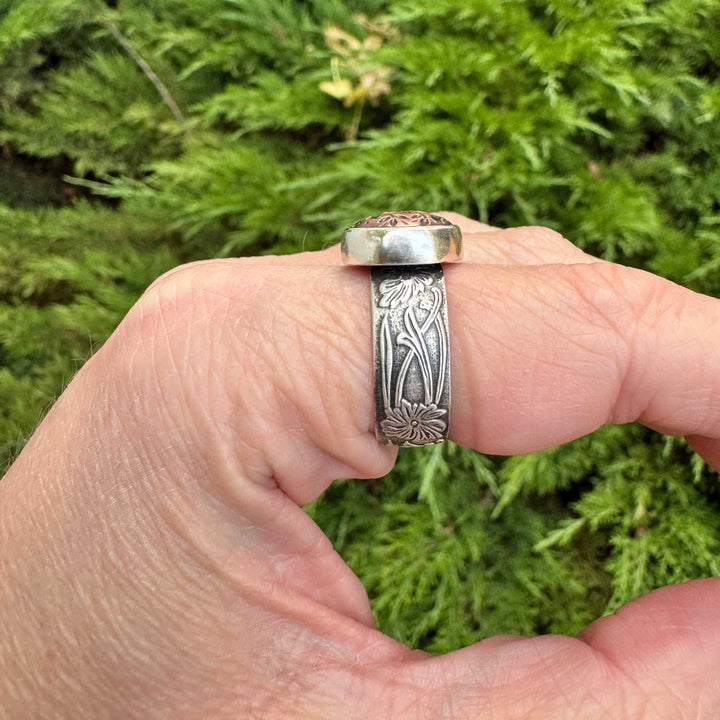 Side view of a sterling silver Gothic initial ring showing the raised copper letter and stepped bezel construction.