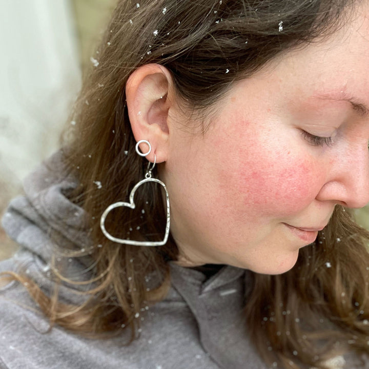 Sterling silver heart hoop earrings worn on woman in snow showing scale and lightweight dangle style