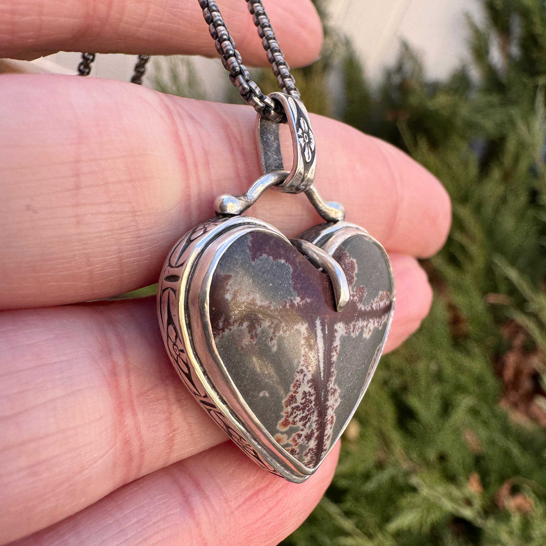 Close-up of dendritic rhyolite heart cabochon in silver bezel setting