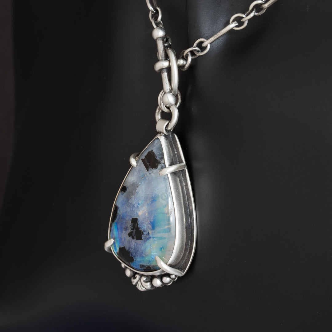 Side angle of sterling silver moonstone pendant showing dimensional metalwork and stone depth