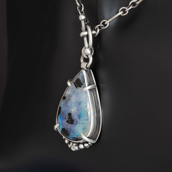 Side angle of sterling silver moonstone pendant showing dimensional metalwork and stone depth