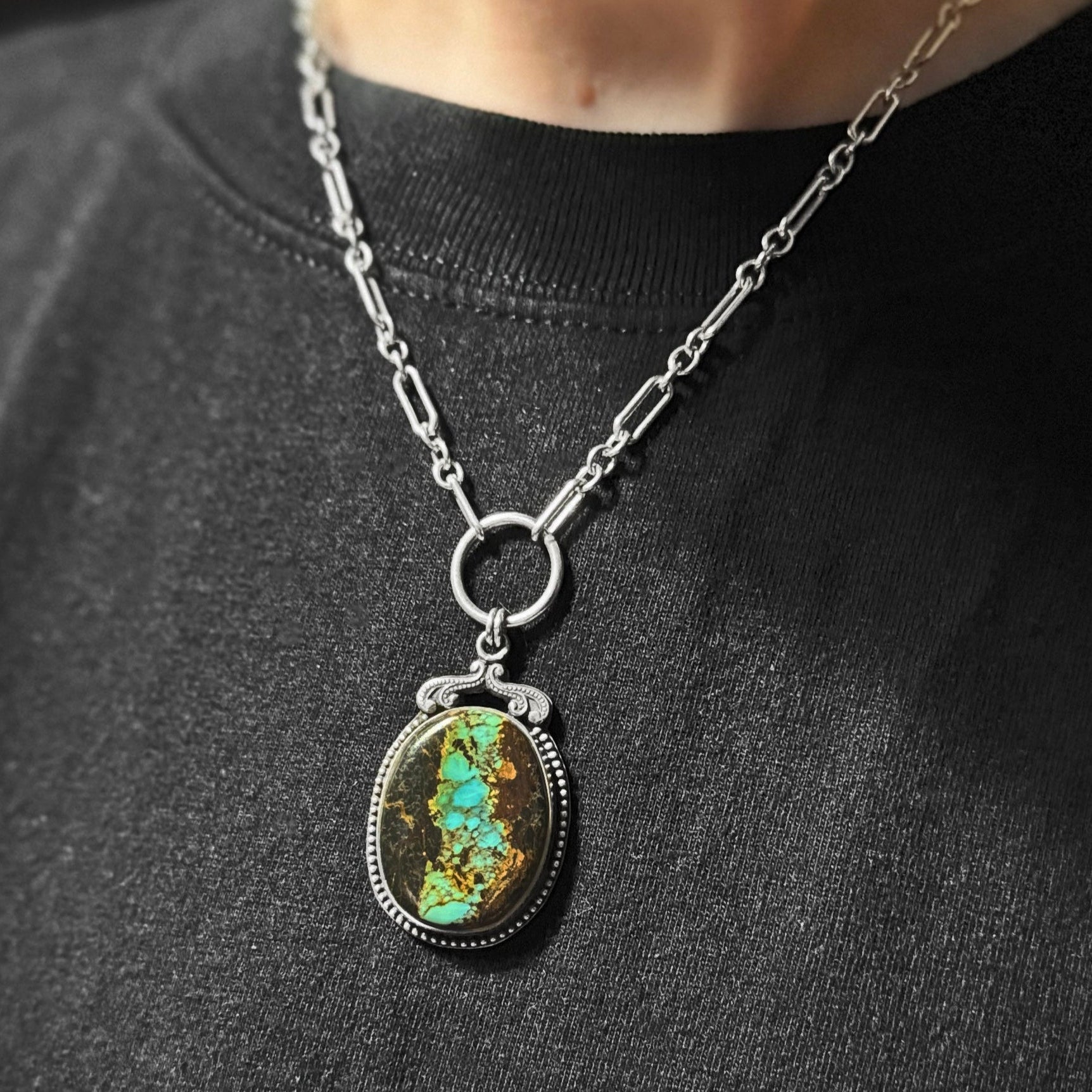 Handcrafted Blackjack Turquoise statement pendant necklace featuring genuine Nevada turquoise stone with vibrant blue-green turquoise in dramatic black matrix, set in sterling silver beaded bezel with art nouveau inspired crown detail, hanging from a silver paperclip chain with O-ring connector