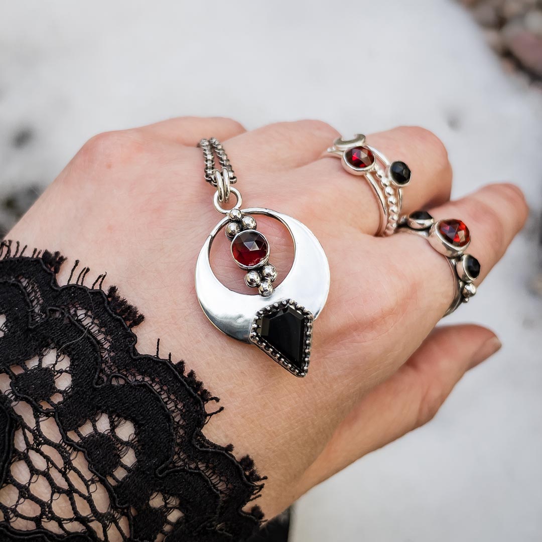 One-of-a-kind garnet and black onyx necklace with silver gothic bat design.