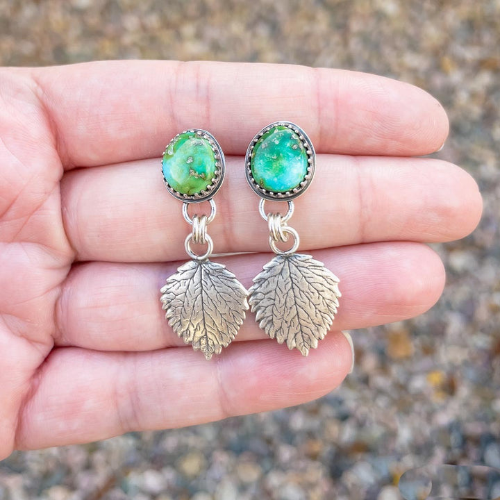 Sonoran Gold turquoise and sterling silver aspen leaf earrings displayed in hand.