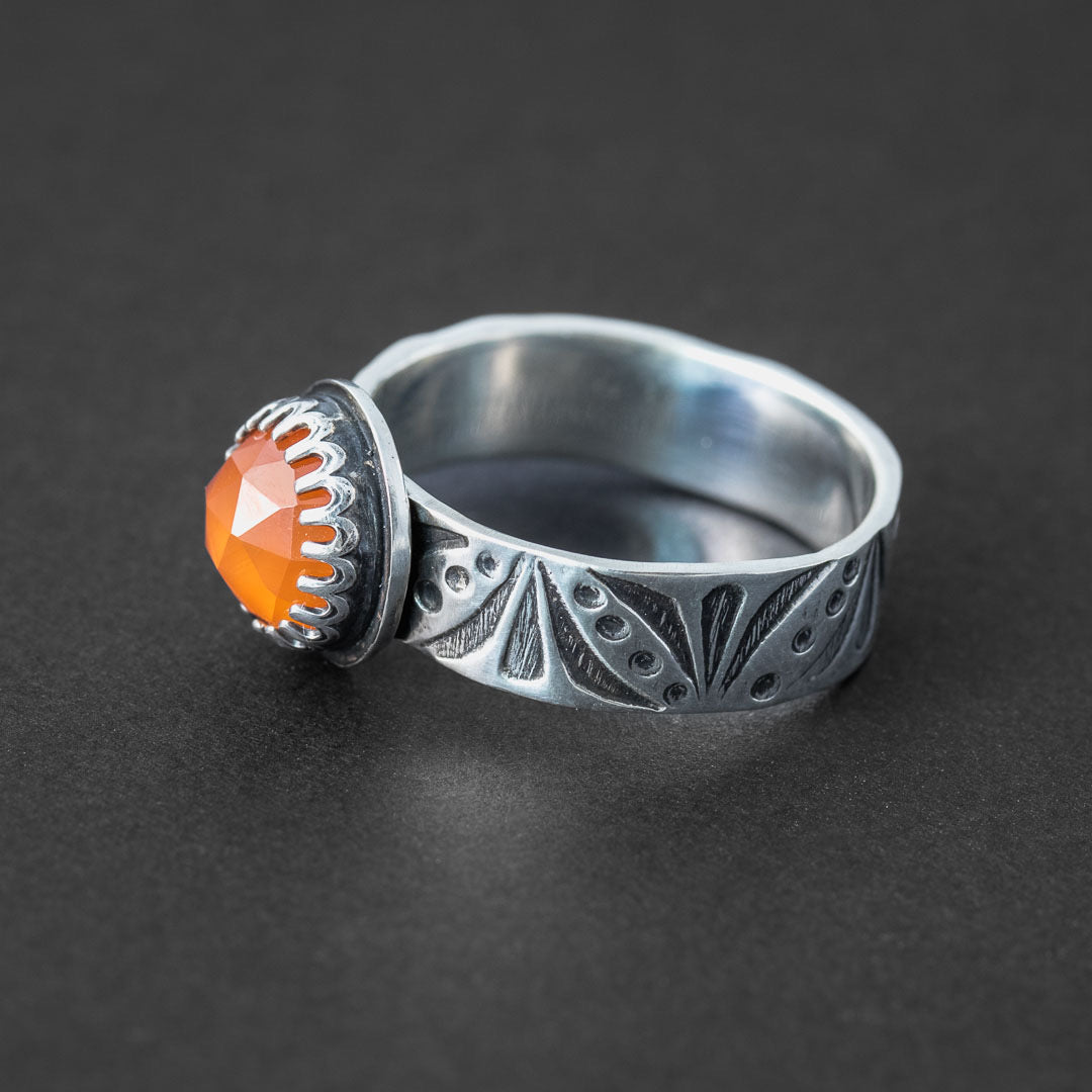 A carnelian stone ring with a hand stamped ring band in sterling silver. Hand made jewelry in Fort Collins, Colorado.