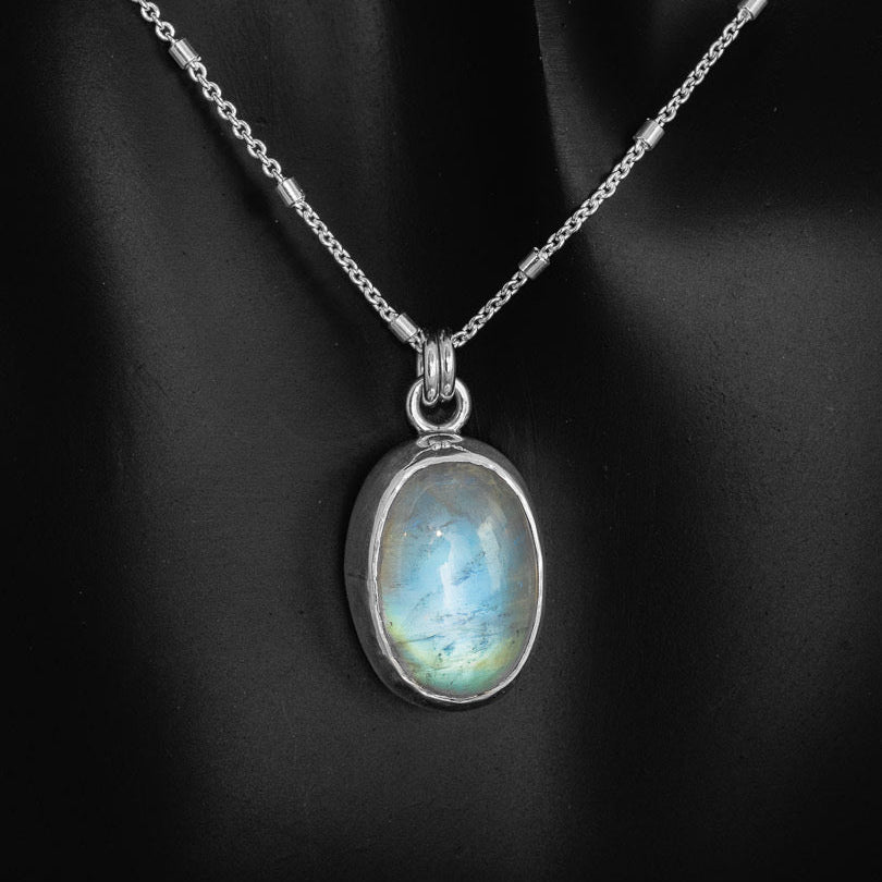 A rainbow moonstone pendant necklace hanging from an 18 inch sterling silver chain. Handmade in Fort Collins, Colorado.