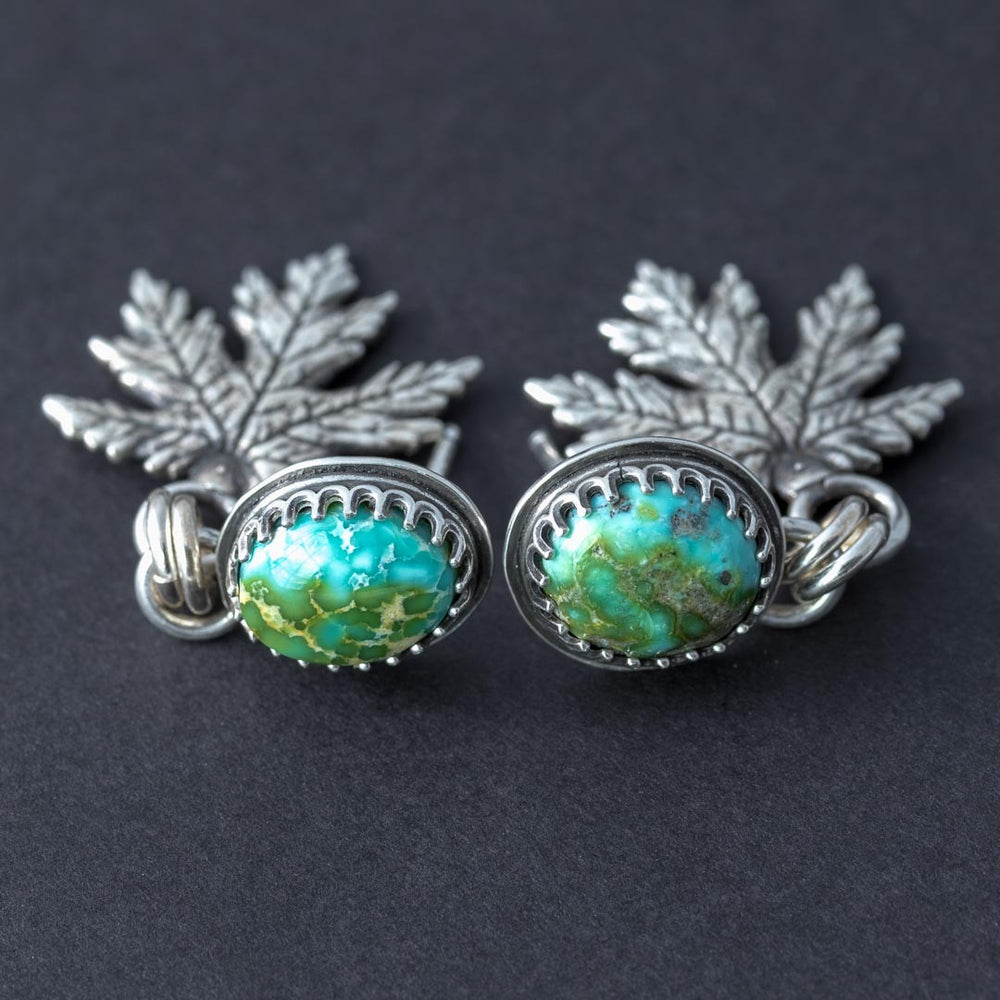 Close-up of Sonoran Gold turquoise stud earrings with serrated bezel and silver leaf charms