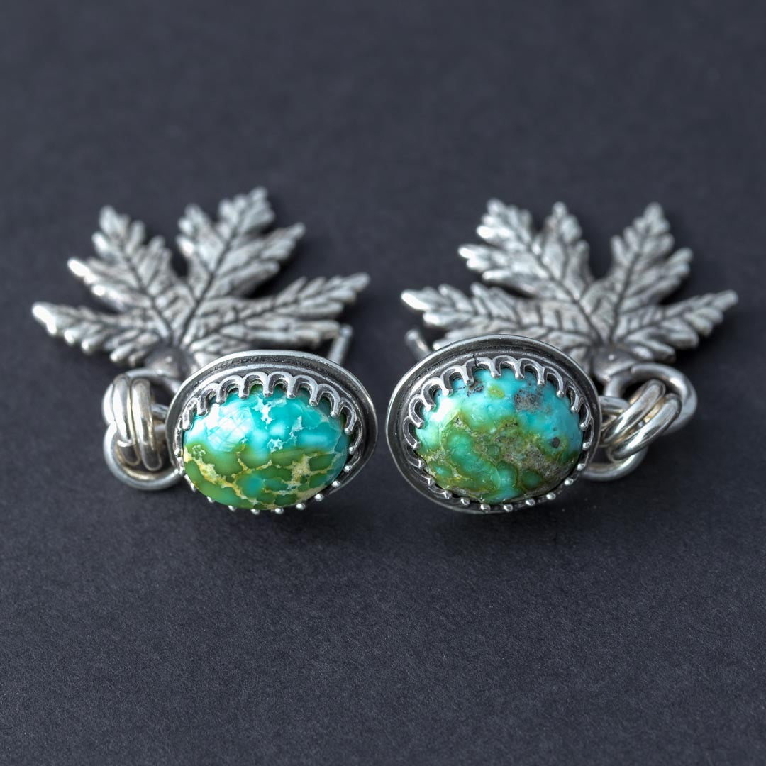 Close-up of Sonoran Gold turquoise stud earrings with serrated bezel and silver leaf charms