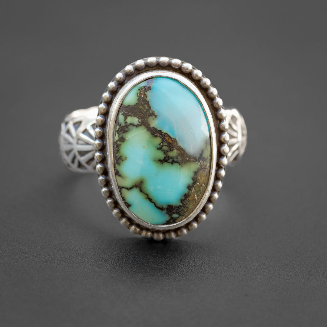 A lovely blue-green turquoise ring in size 7. It is sterling silver with a southwestern stamped ring band.